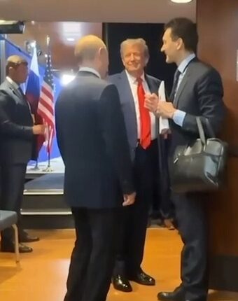 Putin and Trump speaking with others in a hallway.