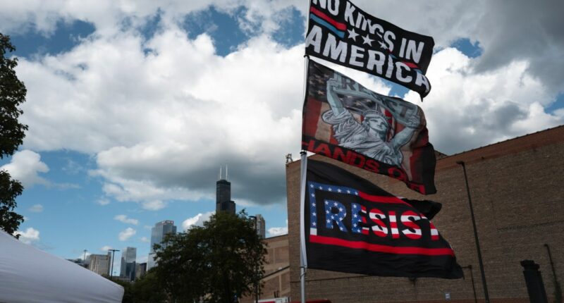 Bernie Sanders signs flying in foreground, Chicago skyscrapers in the background amid clouds