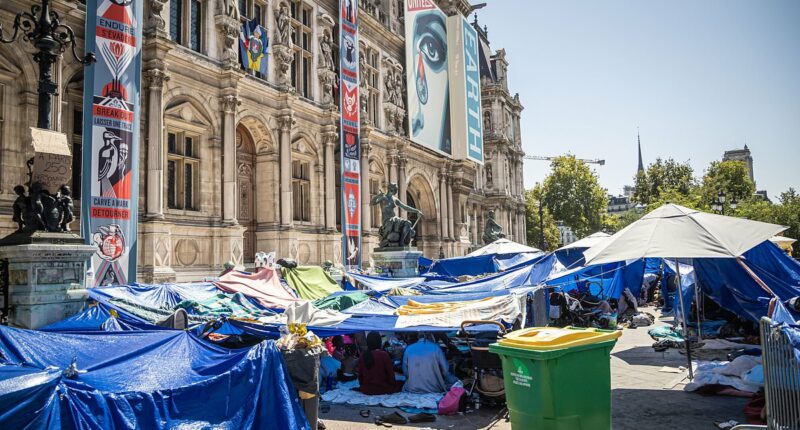 Inside Paris's latest migrant camp: Families sleep on the floor beneath tarpaulin sheets outside French capital's city hall as they wait to be given housing