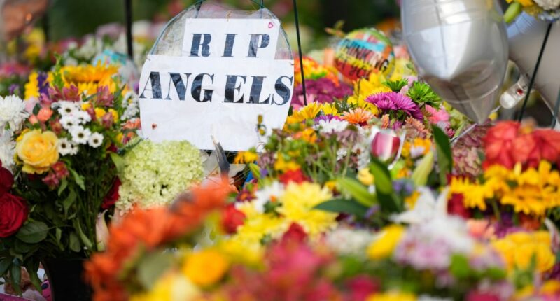 A sign reading "RIP Angels" sits amid flowers at a memorial at Annunciation Catholic Church