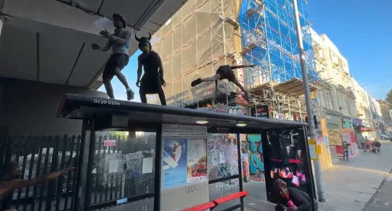 Notting Hill Carnival revellers dance on the top of a bus stop as thousands kick off celebrations at dawn
