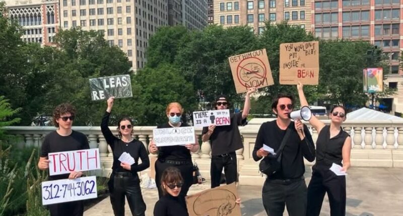 Protestors holding signs demanding a man be freed from a bean-shaped structure.