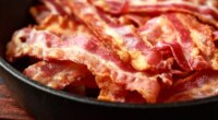 Fried crunchy Streaky Bacon pieces in a cast iron skillet