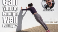 Sporty woman doing press ups against a white wall outside. Over 40? If You Can Do This Many Wall Pushups, Your Strength Is Above Average. Cover