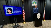 Austin police official stands at podium next to TV screen showing arrested suspect's mugshot
