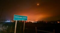 A fire blazes behind a sign reading "Chinese Camp."