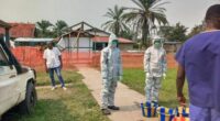 Men stand outside an Ebola treatment center in the remote Bulape Health Zone, Kasaï province, the Democratic Republic of Congo