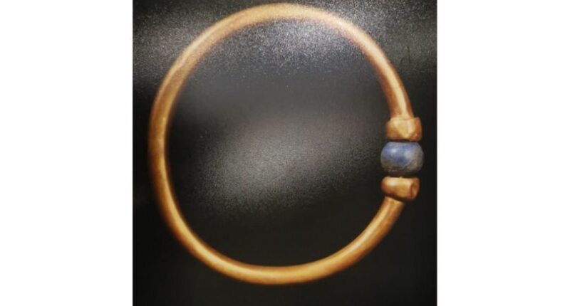 A gold bracelet with a blue bead on it