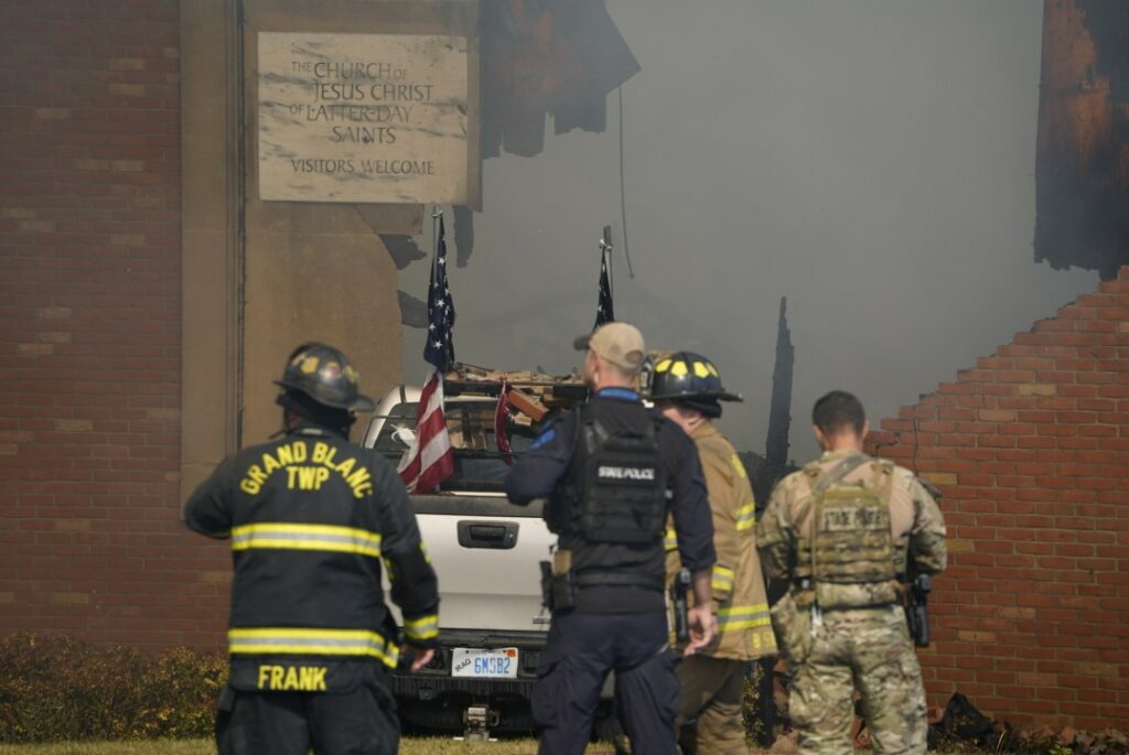First responders stand behind the truck crashed into the Church of Latter-day Saints in Grand Blanc, Michigan.