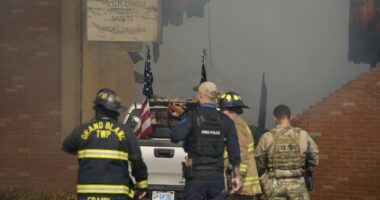 First responders stand behind the truck crashed into the Church of Latter-day Saints in Grand Blanc, Michigan.