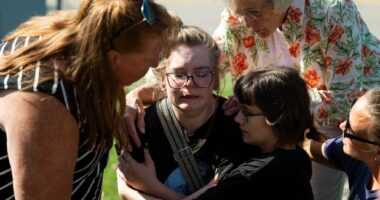People comfort each other at the scene of a shooting and fire at a church in Michigan
