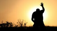 A man lifts his hand towards heaven. Silhouette, rear view, unrecognizable person. Additional themes include salvation, god, praise and worship, holiness, righteousness, faith, sin, forgiveness, gratitude, meditation, prayer, self, asking, pleading, hope, heaven, healing, spirituality, balance, religious, and Christianity.