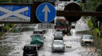 Vehicles drive through a flooded road.