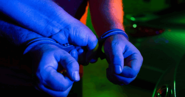 Two hands in police handcuffs.