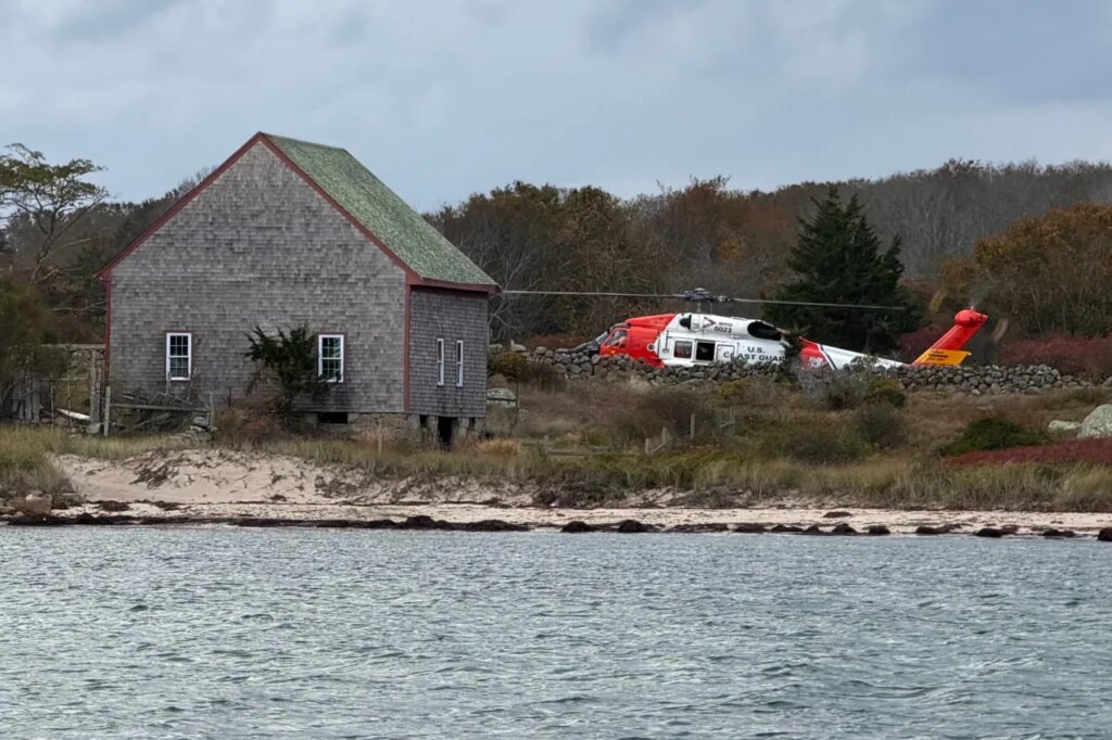 A U.S. Coast Guard helicopter approaches Naushon Island, Mass. Wednesday, Oct. 22, 2025, where a couple and their adult son were rescued two days after their boat caught fire and they swam to shore. (U.S. Coast Guard via AP)