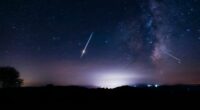 Milky Way stars with meteor shower trails and countryside silhouettes.