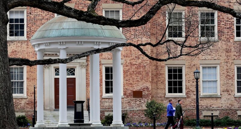 FILE - People walk through University of North Carolina campus March 18, 2020, in Chapel Hill, N.C. (AP Photo/Gerry Broome, File)
