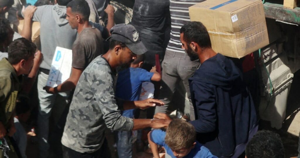 Palestinians crowd onto aid trucks moving through Gaza