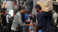 Palestinians crowd onto aid trucks moving through Gaza