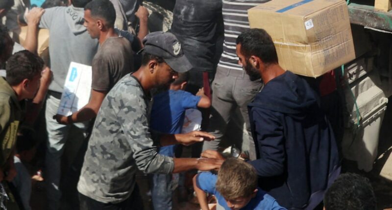 Palestinians crowd onto aid trucks moving through Gaza