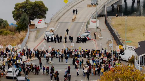 EDS NOTE: OBSCENITY - Protesters block the entrance to Coast Guard Base Alameda shortly after a caravan of U.S. Customs and Border Protection personnel arrived on Thursday, Oct. 23, 2025, in Oakland, Calif. (AP Photo/Noah Berger)