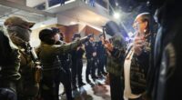 Federal agents, including members of the Department of Homeland Security, and the Border Patrol, hold back protesters outside a downtown U.S. Immigration and Customs Enforcement (ICE) facility.