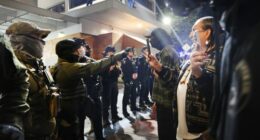 Federal agents, including members of the Department of Homeland Security, and the Border Patrol, hold back protesters outside a downtown U.S. Immigration and Customs Enforcement (ICE) facility.