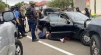 Multiple heavily armed police officers surround a vehicle and a man they arrested in Sydney's south-west.