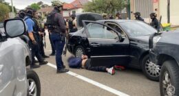 Multiple heavily armed police officers surround a vehicle and a man they arrested in Sydney's south-west.