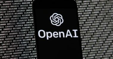 The OpenAI logo appears on a mobile phone in front of a computer screen with random binary data, March 9, 2023, in Boston. (AP Photo/Michael Dwyer, File)