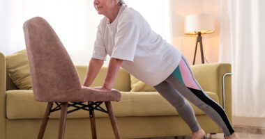 Senior caucasian woman doing yoga at home on chair
