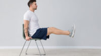 Handsome man exercising with chair at home