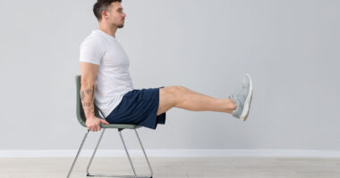 Handsome man exercising with chair at home