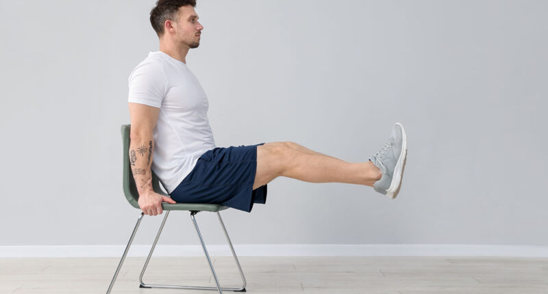 Handsome man exercising with chair at home