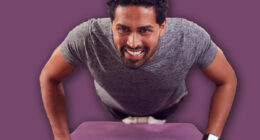 Man In Fitness Clothing At Home In Lounge Doing Press Ups And Exercising With Hand Weights
