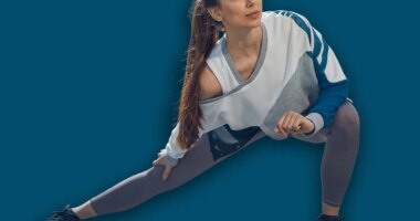 Front view of a young sporty woman with long dark hair doing a side lunge