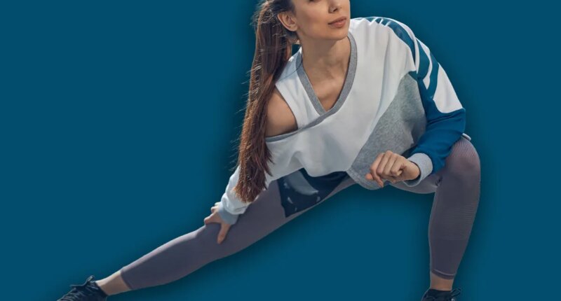 Front view of a young sporty woman with long dark hair doing a side lunge