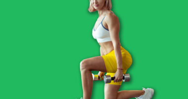Athletic muscular woman trains leg muscles with dumbbells doing lunges in a modern gym. Beautiful female with perfect body. Healthy lifestyle