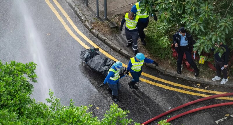 Workers remove a body from a fire which broke out Wednesday at Wang Fuk Court, a residential estate in the Tai Po district of Hong Kong