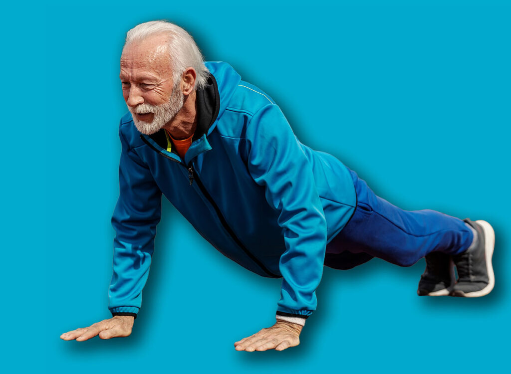 Full length of senior sportsman doing pushups on stadium.