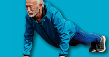 Full length of senior sportsman doing pushups on stadium.