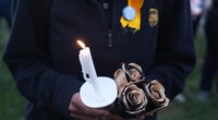 An attendee holds a candle and flowers during a vigil Thursday, Nov. 6, 2025, in Louisville, Ky., after a UPS plane crashed at Louisville Muhammad Ali International Airport. (AP Photo/Darron Cummings)