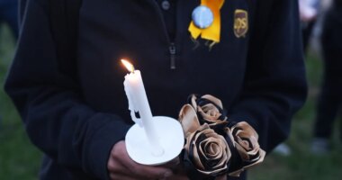 An attendee holds a candle and flowers during a vigil Thursday, Nov. 6, 2025, in Louisville, Ky., after a UPS plane crashed at Louisville Muhammad Ali International Airport. (AP Photo/Darron Cummings)
