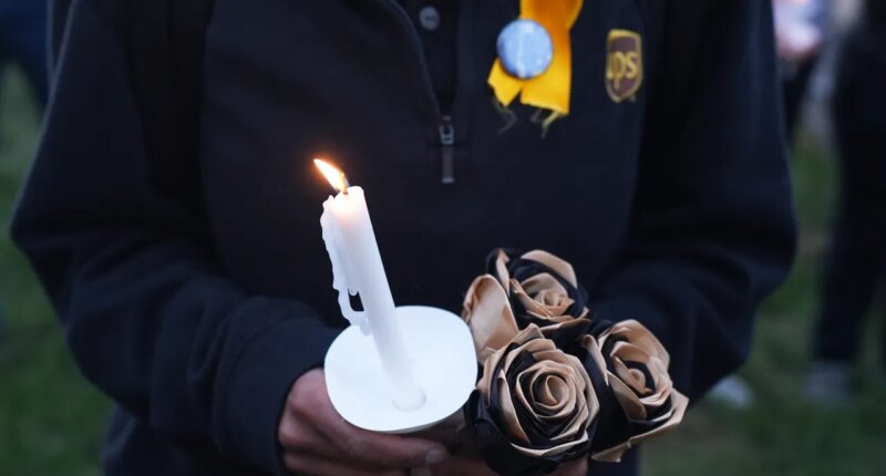An attendee holds a candle and flowers during a vigil Thursday, Nov. 6, 2025, in Louisville, Ky., after a UPS plane crashed at Louisville Muhammad Ali International Airport. (AP Photo/Darron Cummings)