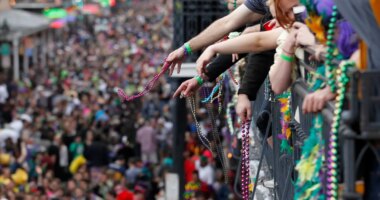 FILE - Revelers throw beads from the balcony of the Royal Sonesta Hotel onto crowds on Bourbon Street during Mardi Gras festivities in the French Quarter in New Orleans, March 8, 2011. (AP Photo/Gerald Herbert, File)