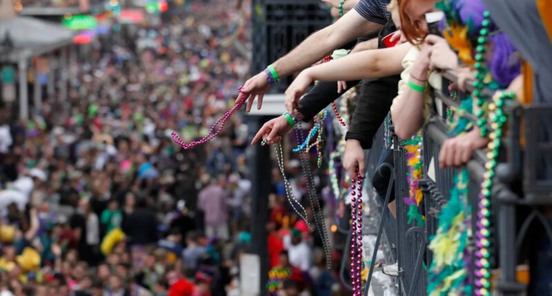 FILE - Revelers throw beads from the balcony of the Royal Sonesta Hotel onto crowds on Bourbon Street during Mardi Gras festivities in the French Quarter in New Orleans, March 8, 2011. (AP Photo/Gerald Herbert, File)