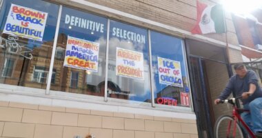 FILE - A bicyclist passes Definitive Selection clothing store, one of many businesses in the predominantly Latino neighborhood that has seen a slowdown in foot traffic since President Donald Trump