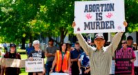 FILE - A man supporting restrictions on abortion holds a sign as abortion-rights supporters hold signs behind him outside the South Carolina Statehouse on Thursday, July 7, 2022, in Columbia, S.C. (AP Photo/Meg Kinnard, File)