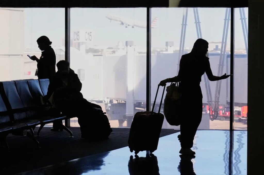 Travelers wait at a gate for their departing flight at the Dallas Fort Worth International Airport, at DFW Airport, Texas, Friday, Nov. 21, 2025. (AP Photo/Tony Gutierrez)