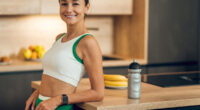 Happy woman in sportswear standing in home kitchen after doing workout